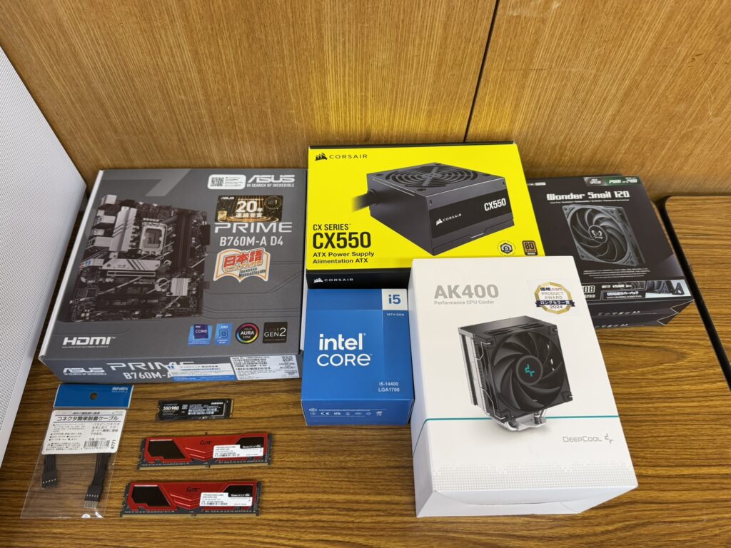 "PC自作に使うパーツ一式。白いケースASUS Prime AP201とマザーボード、CPU、電源、CPUクーラーの箱を並べた様子"